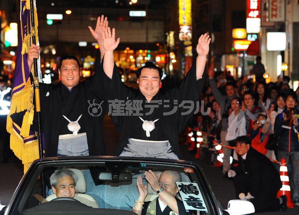 初優勝を果たして横綱昇進を確実にし、優勝パレードで万歳をしながら笑顔をみせる大関鶴竜（かくりゅう、中央）。左は十両で初優勝した元小結の豊真将（ほうましょう）＝２０１４年３月２３日夜、大阪市浪速区（山田耕一撮影）