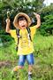 シーサーのＴシャツを着た男の子と出会いました。Ｔシャツの黄色が映える背景を選び、緑色をバックに撮影させてもらいました＝沖縄県宮古島市（須藤夕子さん撮影）