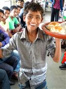 バングラデシュでは冬に食べられるという温かいお菓子「ババピタ」を売る少年