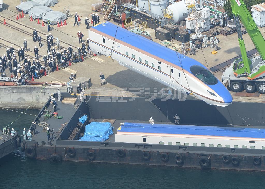 クレーンで台船に積み込まれる北陸新幹線用新型車両Ｗ７系＝７日午前、神戸市兵庫区（本社ヘリから、大塚聡彦撮影）