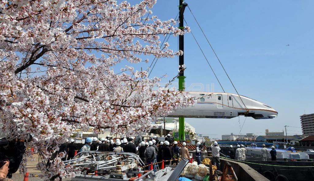 クレーンでつり上げられ工場から搬出される北陸新幹線新型車両Ｗ７系＝７日午前、神戸市兵庫区の川崎重工業兵庫工場（頼光和弘撮影）