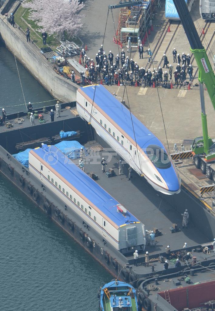 クレーンでつり上げられ、台船に積み込まれる北陸新幹線新型車両Ｗ７系＝７日午前、神戸市兵庫区の川崎重工業兵庫工場（本社ヘリから、大塚聡彦撮影）