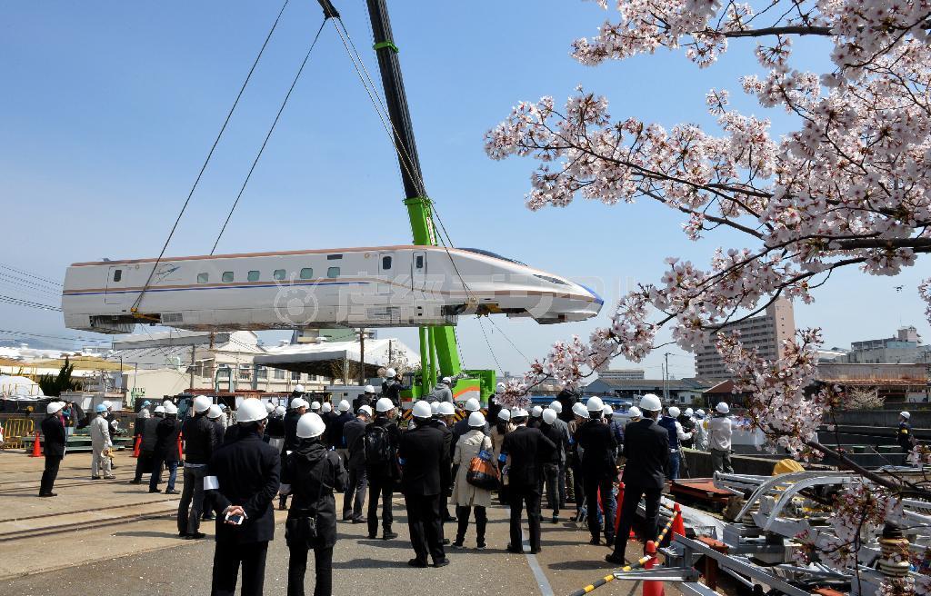 クレーンでつり上げられ工場から搬出される北陸新幹線新型車両Ｗ７系＝７日午前、神戸市兵庫区の川崎重工業兵庫工場（頼光和弘撮影）