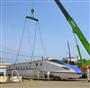 クレーンでつり上げられ工場から搬出される北陸新幹線新型車両Ｗ７系＝７日午前、神戸市兵庫区の川崎重工業兵庫工場