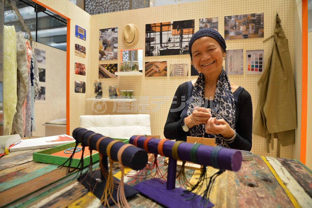 気さくな笑顔のチャン・ルーさん。工房を模したスペースで、器用な手つきでブレスレッドを編んで見せてくれた＝２０１４年４月５日、東京都千代田区の大丸東京店（原田史郎撮影）