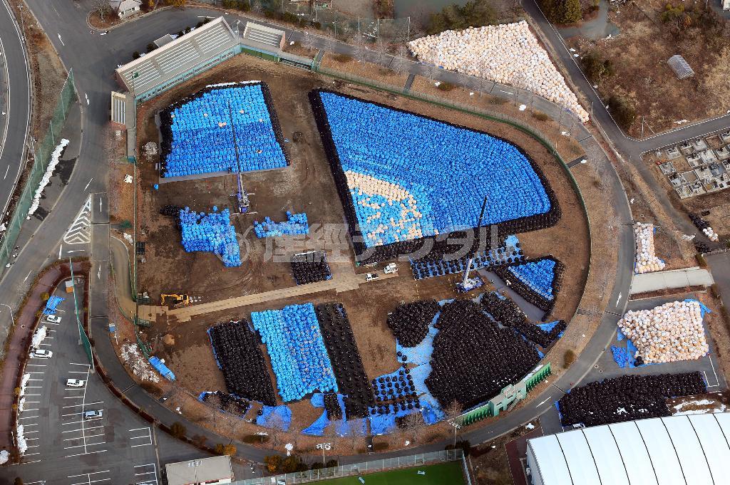 福島第１原発近くの双葉総合公園のスタジアムは除線作業で出た放射性廃棄物の大袋の置き場となっていた。青色が除線廃棄物、黒色と白色は遮蔽土嚢（どのう）だという＝２０１４年２月２０日、福島県双葉郡双葉町（本社チャーターヘリから、鈴木健児撮影）