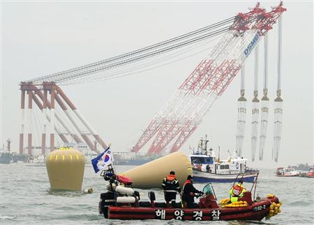 １８日、海面から完全に姿を消した旅客船「セウォル号」の沈没地点に設置されたブイとクレーン船（奥）＝韓国南西部・珍島沖（共同）