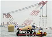 １８日、海面から完全に姿を消した旅客船「セウォル号」の沈没地点に設置されたブイとクレーン船（奥）＝韓国南西部・珍島沖（共同）