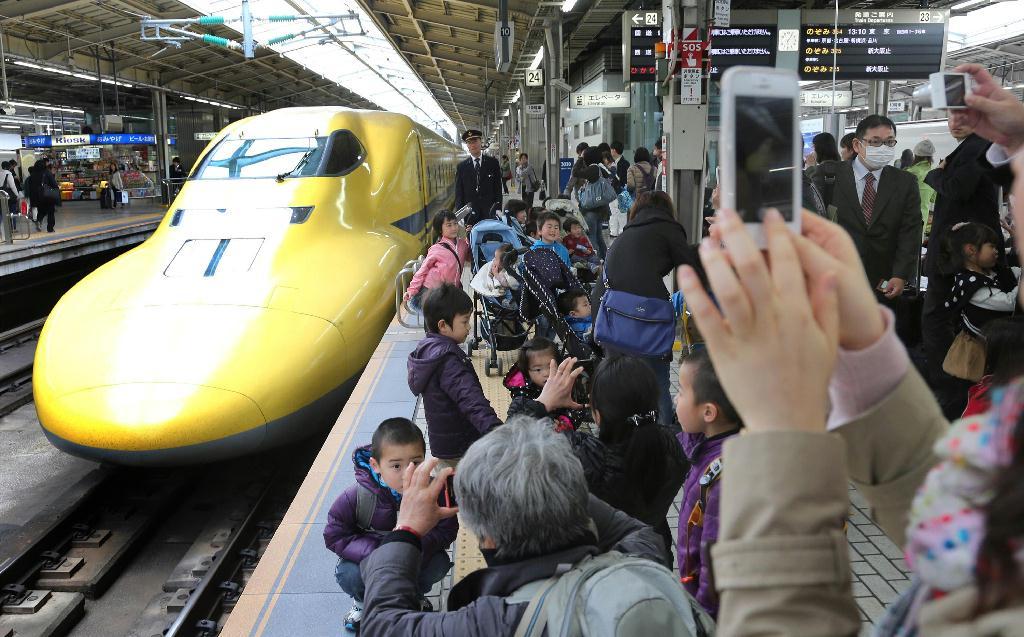 東京駅を出発、西へ向かうドクターイエロー。黄色い車体が都心のビル街に映える＝東京・有楽町