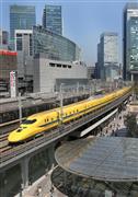 東京駅を出発、西へ向かうドクターイエロー。黄色い車体が都心のビル街に映える＝東京・有楽町