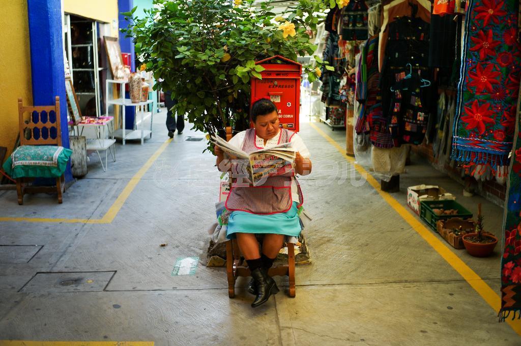 土産物屋が軒を連ねるマーケットで新聞を読む店員の女性＝メキシコ・首都メキシコシ市（緑川真実さん撮影）