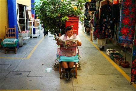 土産物屋が軒を連ねるマーケットで新聞を読む店員の女性＝メキシコ・首都メキシコシ市（緑川真実さん撮影）