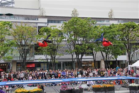 シドニー五輪のトランポリン日本代表の中田大輔さんがトランポリンプレーヤーの川西隆由樹さんとコンビを組んでパフォーマンスを披露。２人が寸分違わないシンメトリーな動きをするアクロバットに観客はくぎ付けとなった。写真は飛び上がりながらズボンをはくパフォーマンス＝２０１４年４月１９日、神奈川県横浜市西区の横浜美術館前（田中幸美撮影）