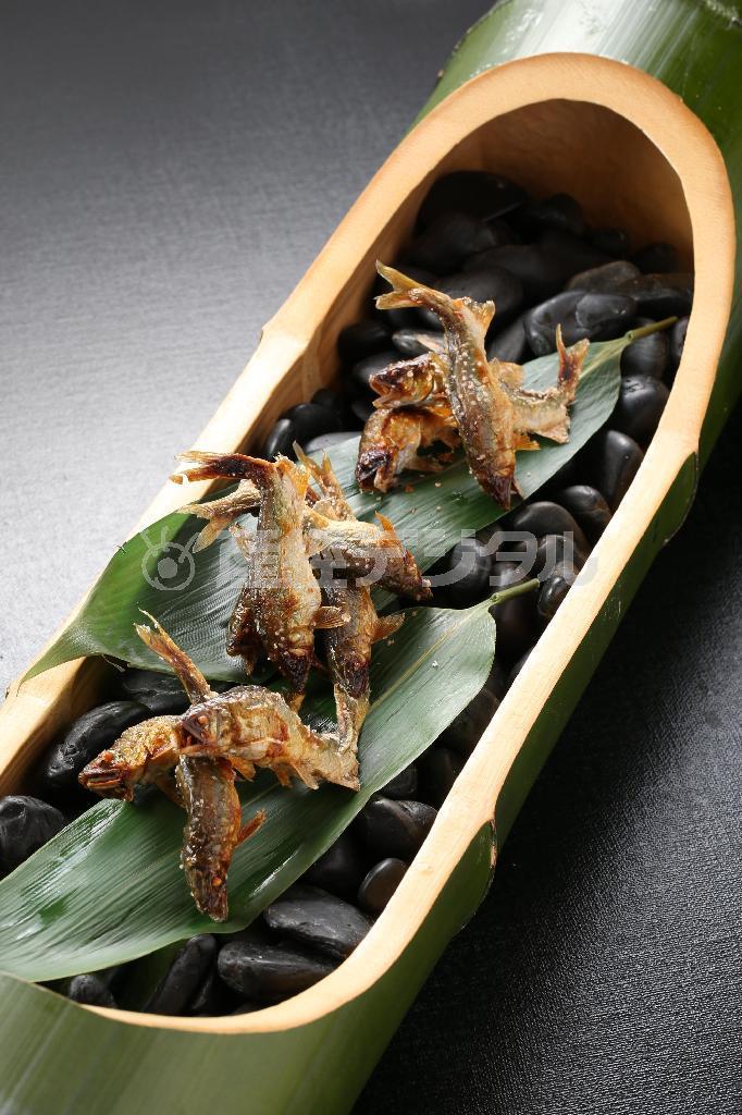 太い竹をそいだ鉢に盛りつけられたアユの塩焼き