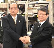 握手する東京都民銀行の柿崎頭取（左）と八千代銀行の酒井頭取＝２日、東京都中央区