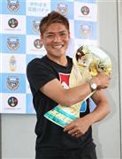 「サプライズ」で２年ぶりに代表に選出された大久保嘉人（よしと）は、ワールドカップ形のパネルを手にして満面の笑みを浮かべた＝２０１４年５月１２日、東京都大田区・羽田空港（春名中撮影）