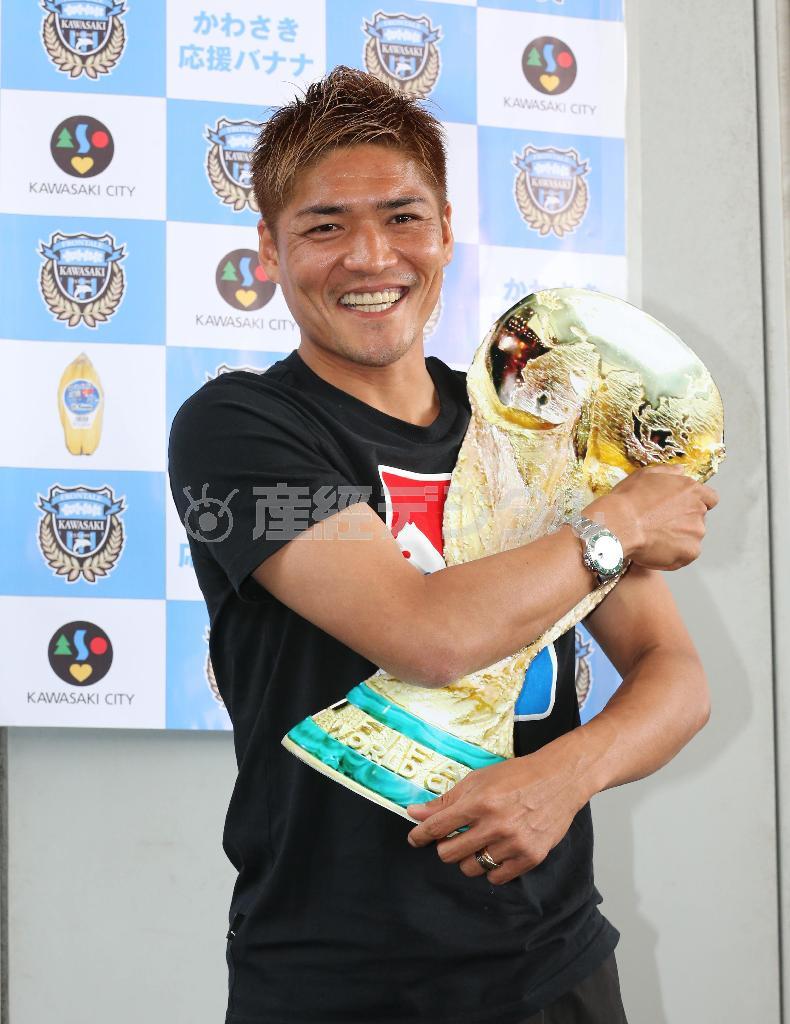 「サプライズ」で２年ぶりに代表に選出された大久保嘉人（よしと）は、ワールドカップ形のパネルを手にして満面の笑みを浮かべた＝２０１４年５月１２日、東京都大田区・羽田空港（春名中撮影）