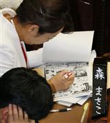 参院本会議で、ペンを片手に漫画「美味しんぼ」のコピーを読む森消費者相＝１４日