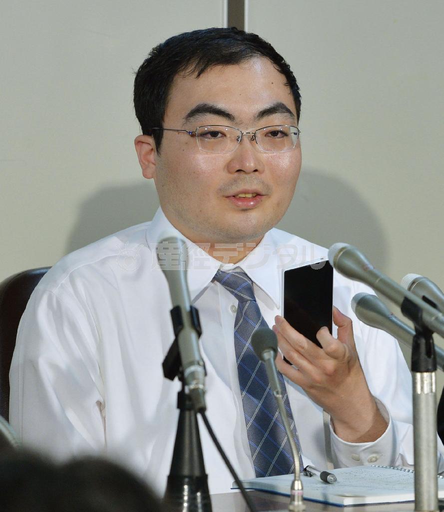 記者会見でスマートフォンを手にして話す片山祐輔被告＝２０１４年５月１６日、東京都千代田区霞が関の司法記者クラブ（共同）