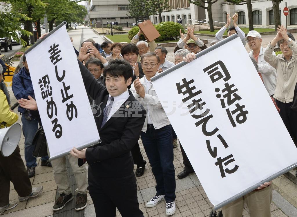 大飯原発３、４号機の運転差し止めを求めた訴訟の判決で、「差し止め認める」などと書かれた垂れ幕を掲げる弁護士ら＝２０１４年５月２１日午後、福井地裁前（共同）