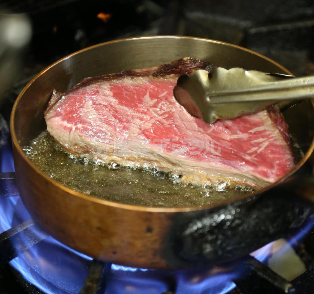 強い火力で、低温と高温の油で揚げ焼きされるステーキ。大きな肉になると、３度は油が替えられる。空いた部分には牛脂を入れクリスピーに焼き上げる