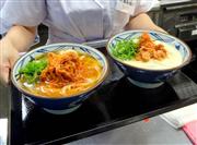 丸亀製麺が夏季限定で売り出す冷かけうどん「旨辛鶏ネギ」（左）と「濃厚豆乳豚キムチ」＝５日、東京都千代田区