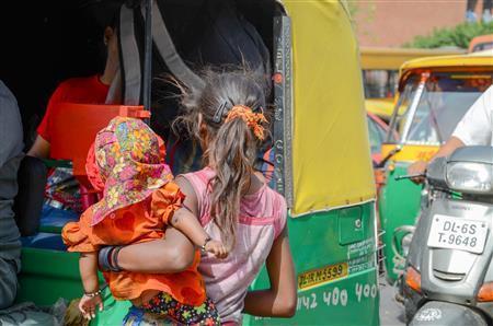 にぎわう通りで物乞いをする女の子。妹だろうか、腕には赤ちゃんを抱いている＝２０１３年４月１２日、インド（ワールド・ビジョン・ジャパン撮影）