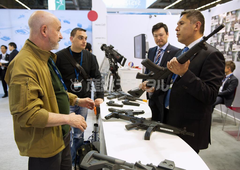 防衛装備品の展示会「ユーロサトリ」に初出展した日本パビリオンで、出展企業の関係者（右）から訓練用のゴム製銃の説明を受ける来場者。日本の防衛産業は歴史的な転換点を迎えた＝２０１４年６月１６日、フランス・首都パリ郊外（共同）