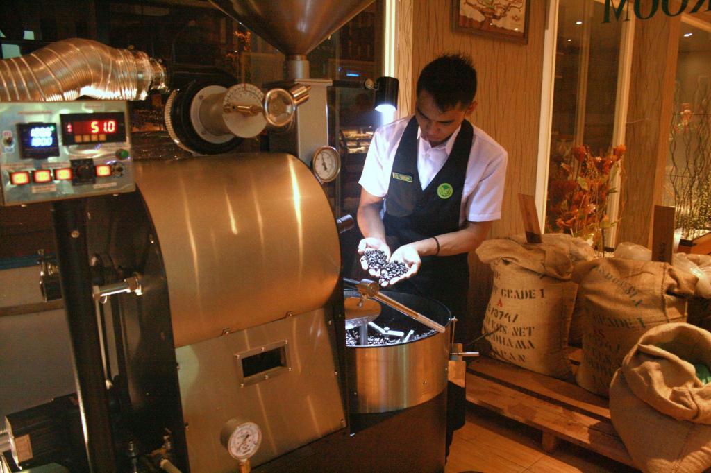 トアルコトラジャコーヒーショップ店内の焙煎（ばいせん）マシンでコーヒー豆の状態をみるバリスタ＝８日、インドネシア・マカッサル