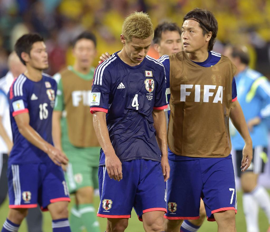 １次リーグ敗退が決まり、うなだれる本田（中央）の肩を抱く遠藤＝クイアバ（共同）