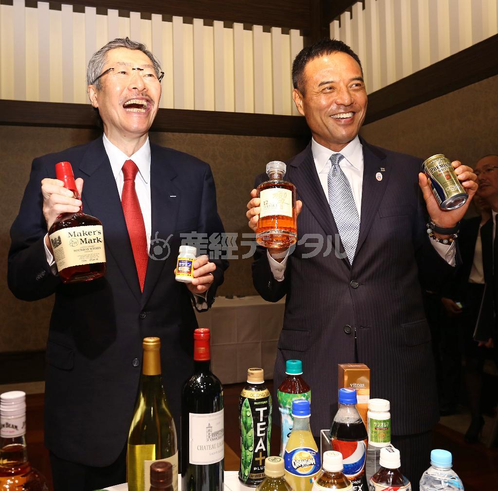 会見後、自社製品を持ち笑顔を見せる佐治信忠（さじ・のぶただ）会長（左）とサントリーＨＤの新社長に決まった新浪剛史（にいなみ・たけし）氏（右）＝２０１４年７月１日午後、東京都港区（大里直也撮影）