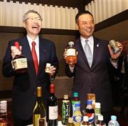 会見後、自社製品を持ち笑顔を見せる佐治信忠（さじ・のぶただ）会長（左）とサントリーＨＤの新社長に決まった新浪剛史（にいなみ・たけし）氏（右）＝２０１４年７月１日午後、東京都港区（大里直也撮影）