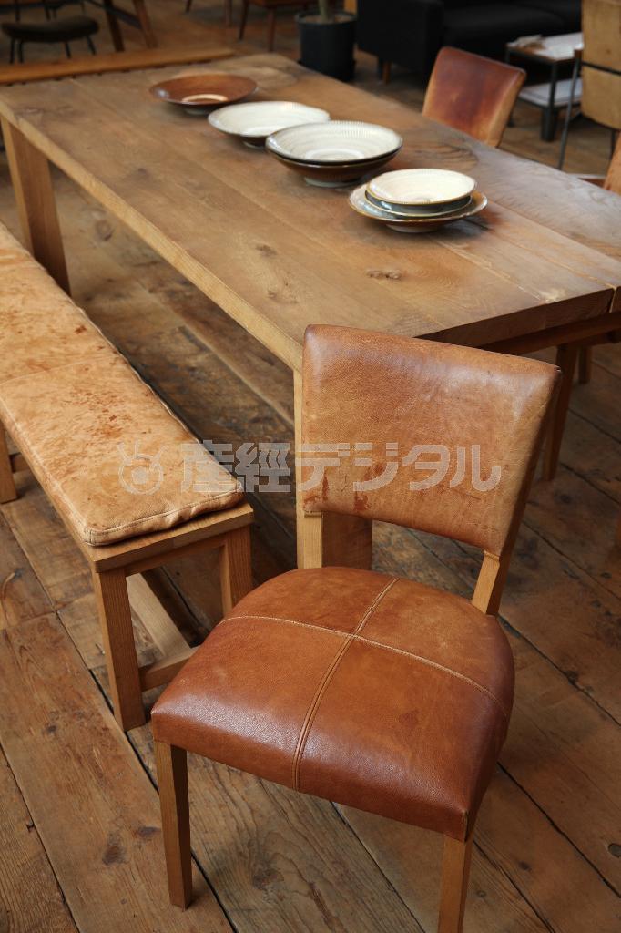 大きな無垢材が使われた「ＯＡＫテーブル」（３６万円）。「ベンチ」（１６万８０００円）、チェア（８万７０００円）にはヌメ革が張られ、使い込むほどに飴色の風体をなす。※価格はすべて税別です＝２０１４年６月１６日、大阪市旭区（村本聡撮影）