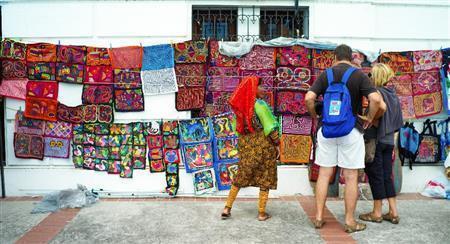 観光客にモラを販売するクナ族の女性。彼女の話では、５歳頃からビーズを足と腕につけ始め、３カ月ごとに交換するという＝パナマ・首都パナマ市（緑川真実さん撮影）