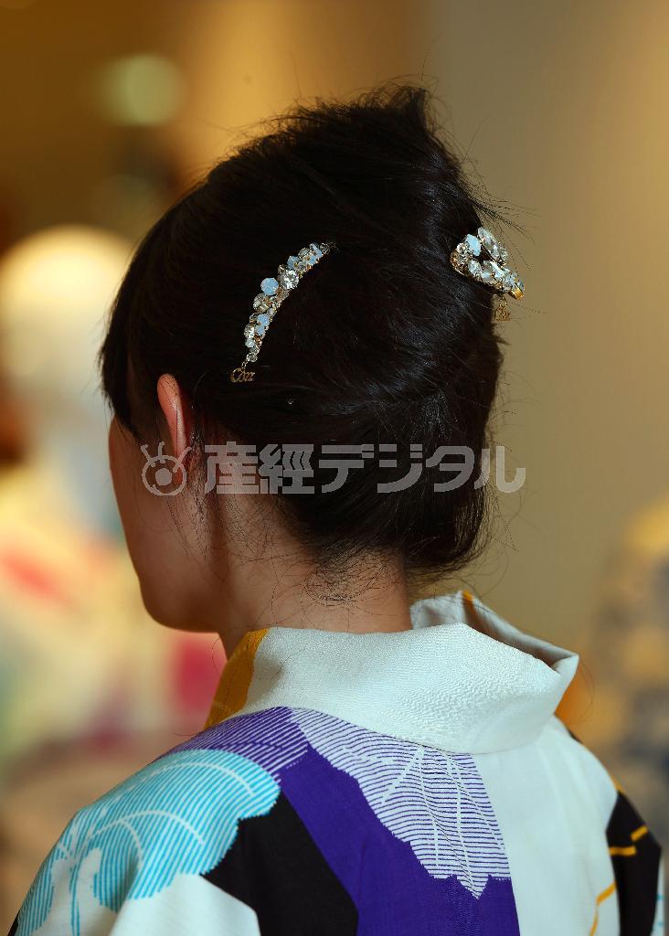 「撫松庵」の浴衣（３万３０００円）と半巾帯（２万３０００円）は、色・柄ミックスで遊び心がたっぷり。帯の後ろ姿のストライプは流行のスポーツテイスト。白い日傘や、透明感のあるヘアアクセサリー（コンプレックスビズ＿右９０００円、左２万円、写真）で涼しげに＝２０１４年６月３０日、東京都中央区・松屋銀座（小野淳一撮影）