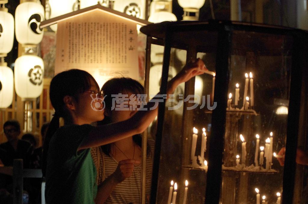 お守りの粽を売っている子供たちから買った蝋燭に火をともし、平安への祈りを捧げる＝２０１３年７月１５日、京都市（井浦新さん撮影）