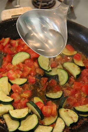 うなぎとズッキーのパスタ（作り方１）＿＿フライパンにオリーブ油、にんにくを入れ、弱火で色づくまで炒め、ズッキーニを加える。ズッキーニがしんなりしてきたらフルーツトマトを加える。煮崩れしてきたら、うなぎ、お玉１～２杯のスパゲティのゆで汁を加え、少し煮詰めて、味を調える。