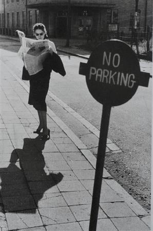 山下町の米軍専用バス停。新聞を読みながらバスを待つサングラスの女性はまるで映画の１シーンから飛び出したよう＝１９５２（昭和２７）年、神奈川県横浜市（奥村泰宏さん撮影、常磐とよ子さん所蔵、提供写真）