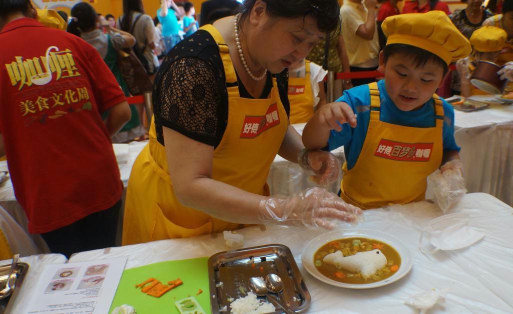 ハウス食品が上海市内のショッピングモールで開いた販促イベント「カレー王国」でカレーライス作りに挑戦する中国人の親子連れ