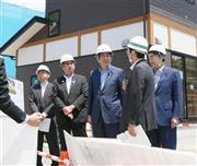 災害公営住宅の建設現場で、説明を受ける安倍晋三（しんぞう）首相（左から３人目）。岩手、宮城、福島の３県では、いまだに約９万人もの被災者がプレハブ仮設住宅での生活を余儀なくされており、工事の加速化は喫緊の課題だ＝２０１４年７月２日、岩手県上閉伊郡大槌町（共同）