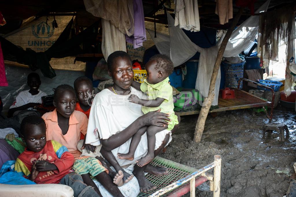 土の上にテントを張り、避難生活を送る親子。足元は非常にぬかるんでいる＝２０１４年７月９日、南スーダン・マラカル（ワールド・ビジョン・ジャパン撮影）