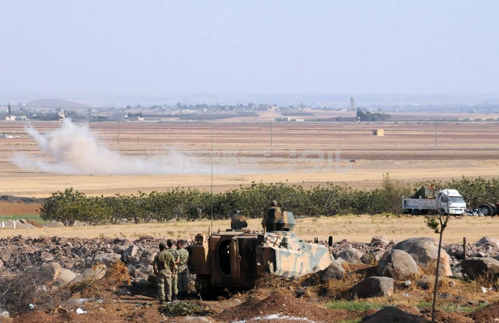 トルコ南部キリス近くのシリアとの国境地帯。トルコ軍の装甲車の向こう側で煙が上がっていた＝２０１４年８月２２日、トルコ・キリス（共同）