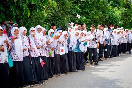 沿道に集まってきた中学生たち。インドネシアは親日家が多く、沿道では日の丸も目立っている＝２０１４年６月、インドネシア・西スマトラ州（田中苑子さん撮影）