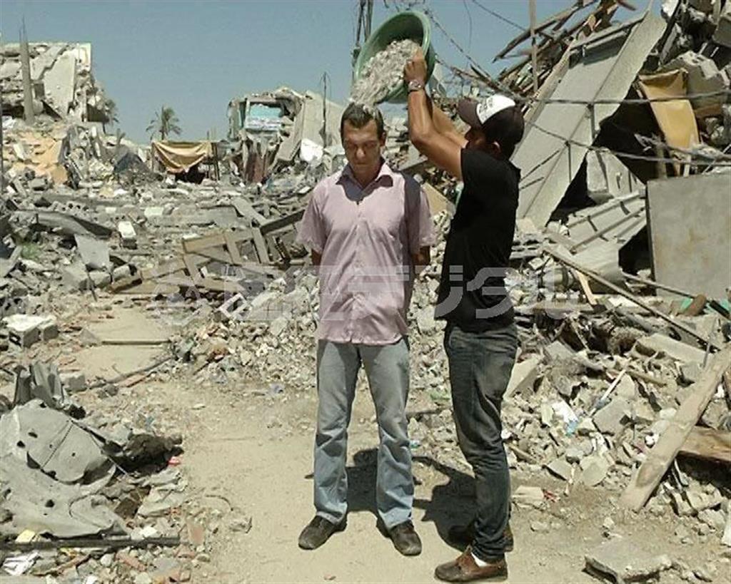 パレスチナ自治区ガザ地区で、氷水ではなく、がれきをかぶるジャーナリストのアイマン・アルール氏＝２０１４年８月２２日、イスラエル（本人提供・共同）