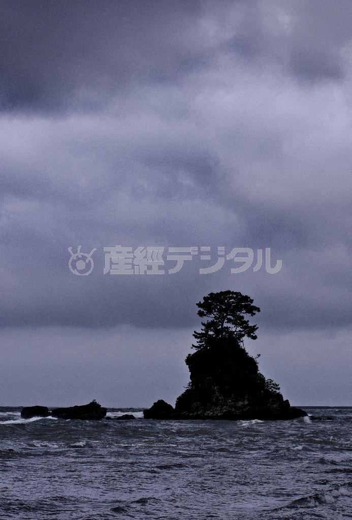 雨晴（あまはらし）海岸から見た女岩。名前に反して、残念ながら雨に煙っていた。まわりの小さな岩と合わせると、母子のように見えることから「女岩」と呼ばれるようになったという＝富山県高岡市（井浦新さん撮影）