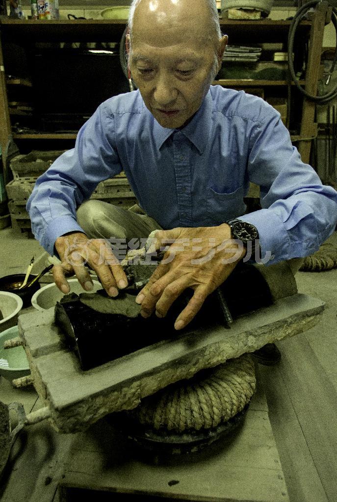 作品の原型を土で型取りする。粘土に和紙の繊維をまぶした土で覆い、そのあと川砂と山砂と粘土を混ぜた土をかぶせる。「外型づくり」と呼ばれる作業をする大澤光民（おおざわ・こうみん）氏＝２０１４年８月９日、富山県高岡市（井浦新さん撮影）