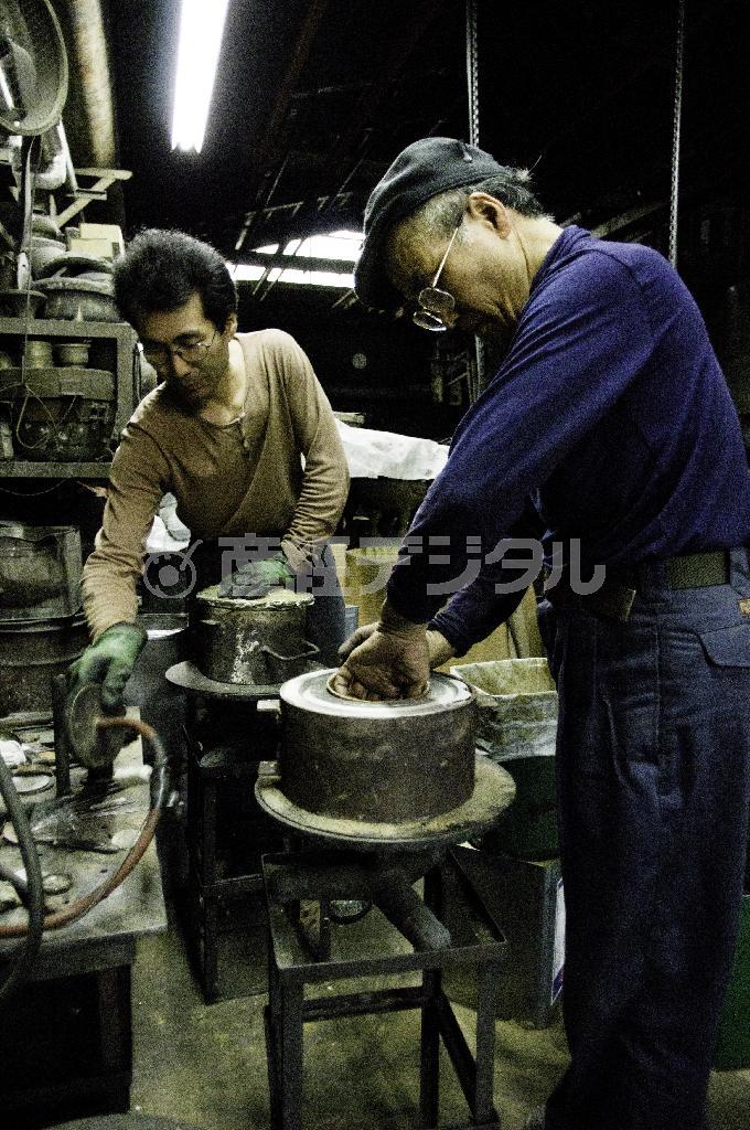 般若保（はんにゃ・たもつ）氏（右）の工房にて、砂型鋳造製法で中子砂型をつくる作業中。砂を込めたら空気を抜き真空にして固める。息子さんの般若泰樹氏（左）も伝統工芸士として活躍しており、未来に向けて技が継承されている＝富山県高岡市（井浦新さん撮影）