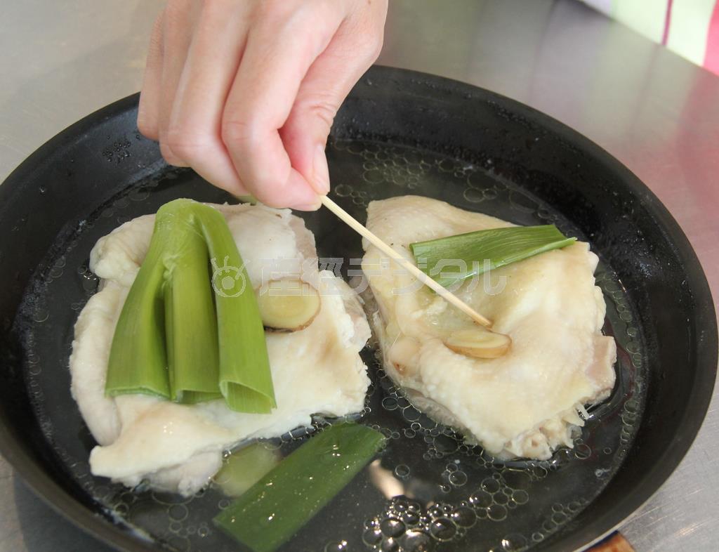 蒸し鶏（作り方２）＿＿調理した鶏もも肉（作り方１：鶏もも肉に塩をもみこむ）を重ならないように鍋に入れて、ねぎ、しょうがをのせ、酒、水を加えて蓋をして強火にかける。沸騰したら弱火で１５分ほど蒸し煮して、火を止め、５分くらい余熱で火を通す（田中幸美撮影）