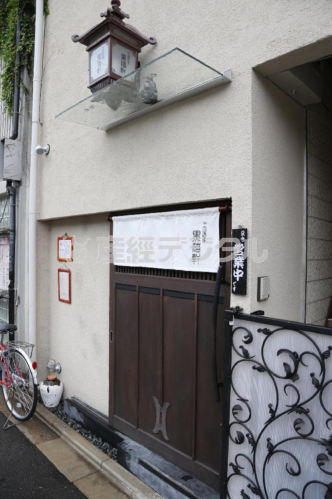 真っ白ののれんに蔵に使われていたという扉。思わず見過ごしてしまいそうな黒猫軒の外観＝２０１４年９月１日、京都市北区（恵守乾撮影）