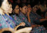 消息不明の航空機と撃墜された航空機の犠牲者を追悼する式典で、涙を拭うマレーシア航空の客室乗務員＝２０１４年７月、マレーシア・首都クアラルンプールのマレーシア航空本社（ロイター）